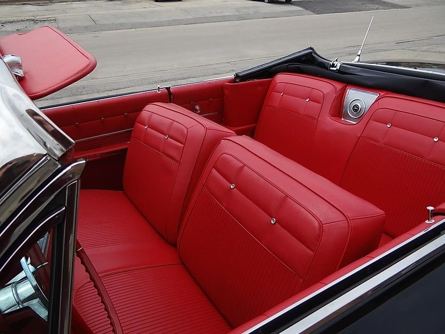 Red leather interior of a classic black convertible car.