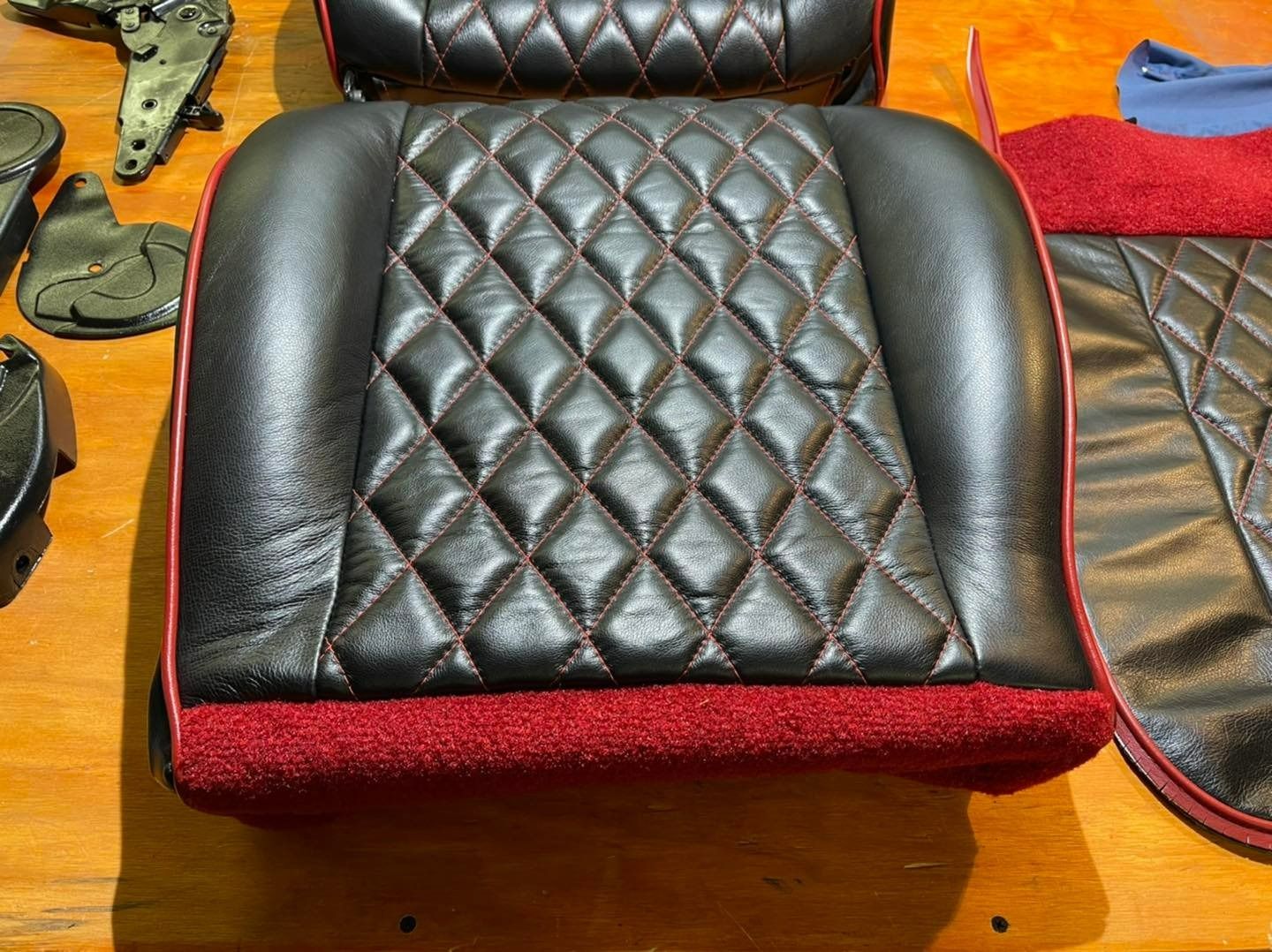 Black leather seat cushion with red diamond stitching and trim.