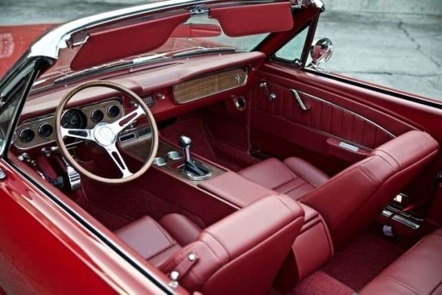 Red convertible car interior with red leather seats, wood paneling, and chrome details.