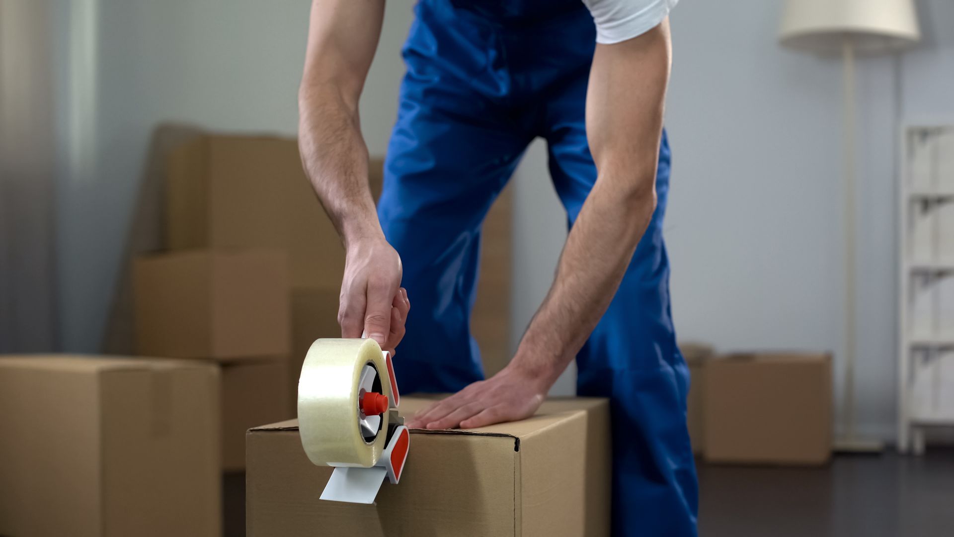 Moving company worker packing cardboard boxes. Moving company worker packing cardboard boxes.
