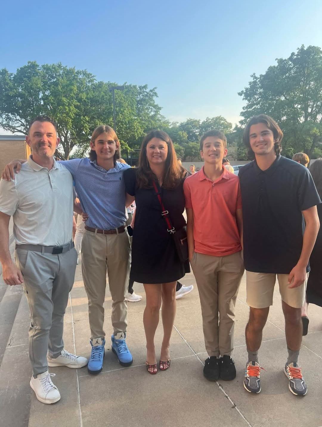 A family is posing for a picture on the porch of their house.