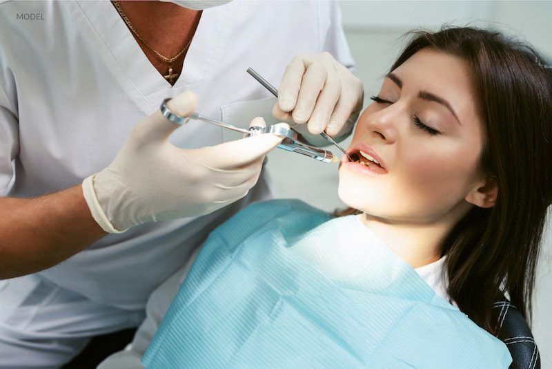 A woman is getting her teeth examined by a dentist.