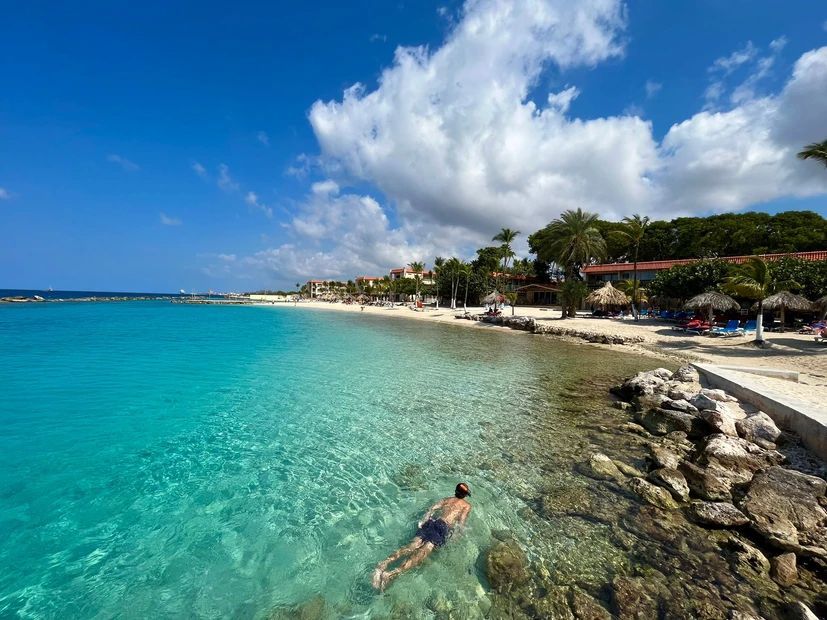 A man is swimming in the ocean near a beach.