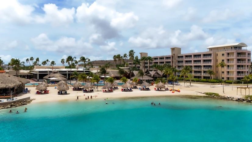 An aerial view of a beach resort with a large building in the background.
