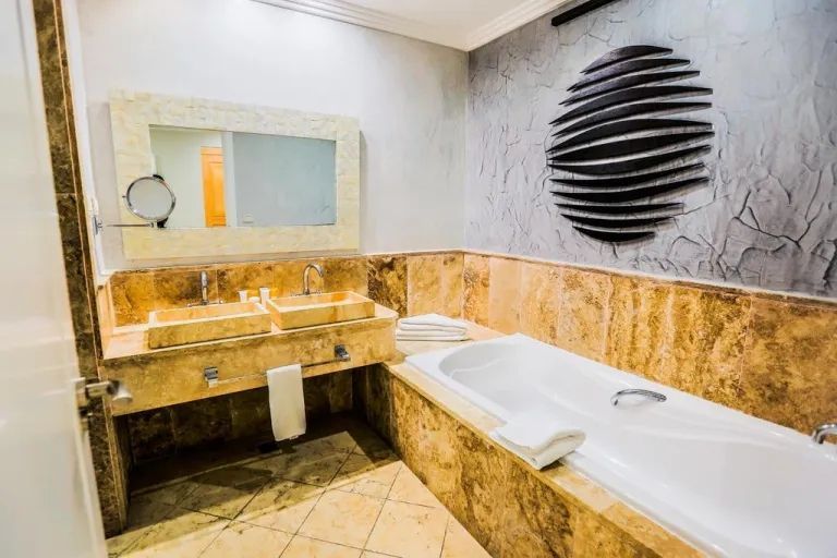 A bathroom with a tub , sink and mirror.