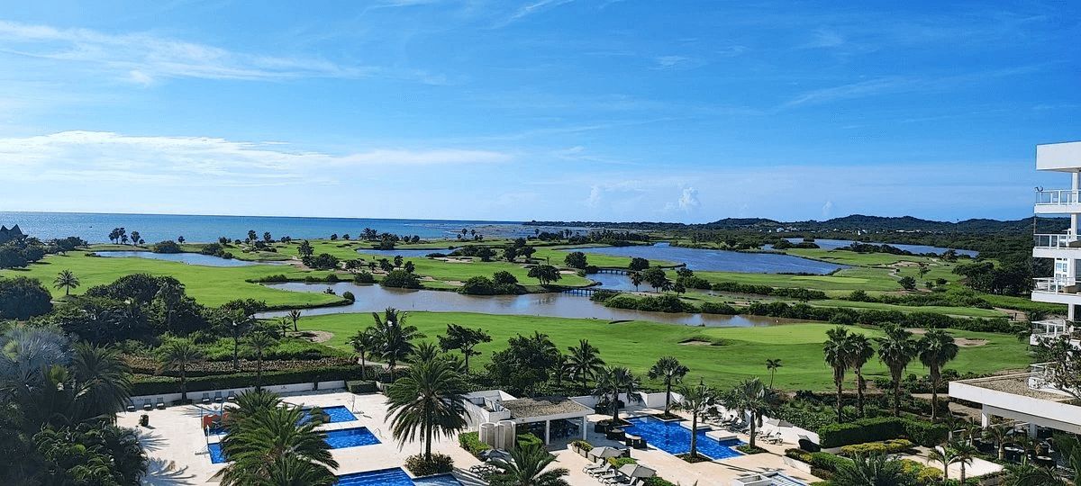 An aerial view of a resort with a golf course and swimming pools.