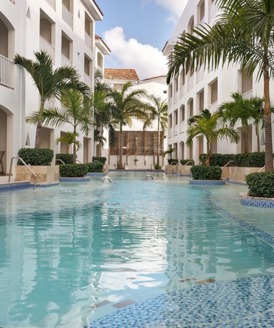 A large swimming pool surrounded by palm trees and buildings