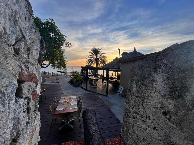 A table and chairs are sitting on a wooden deck next to a large rock.