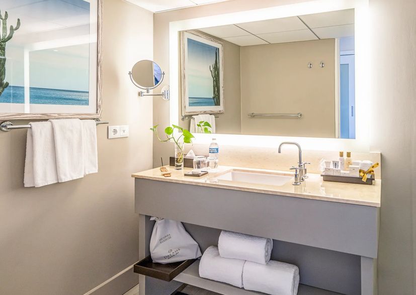 A bathroom in a hotel room with a sink , mirror and towels.