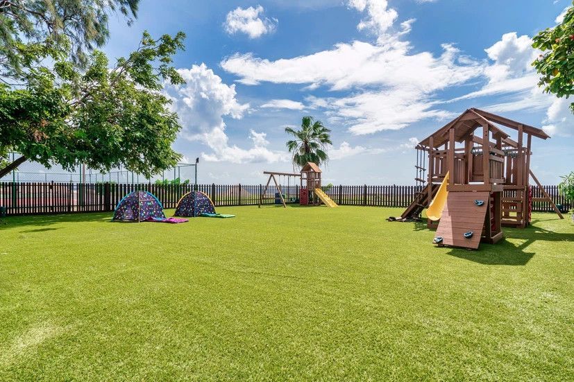 There is a playground in the middle of a lush green field.