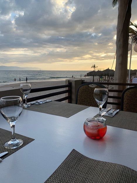 A table with a view of the ocean and two wine glasses on it