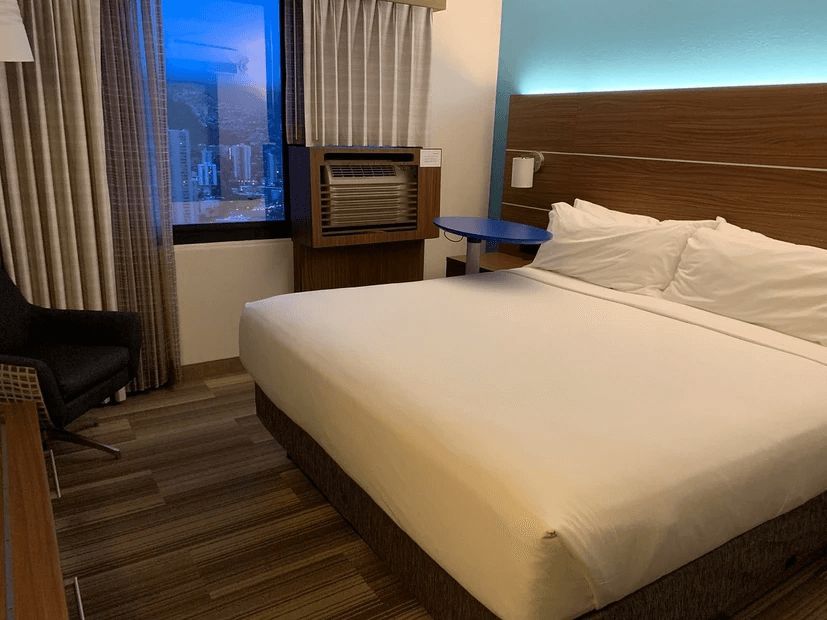 A hotel room with a king size bed and a chair.