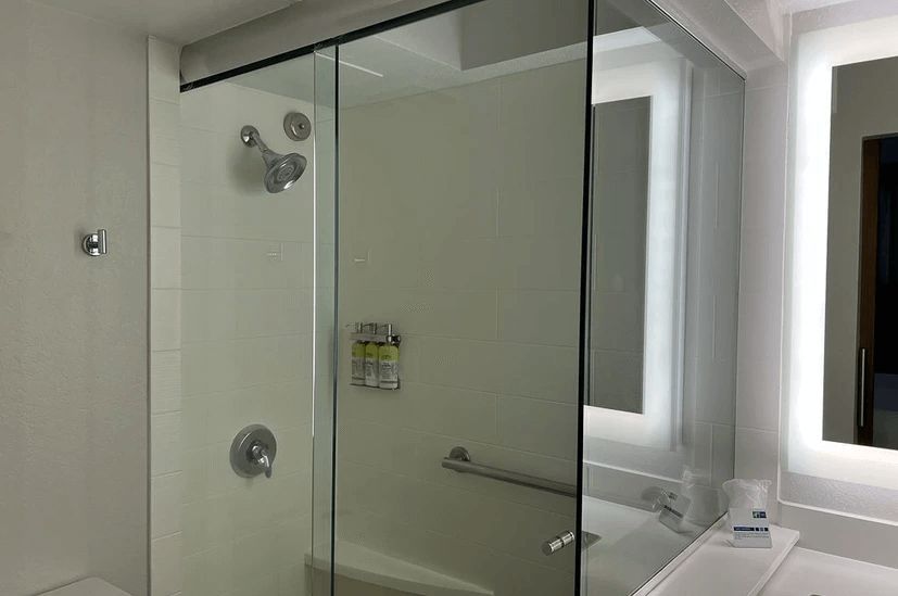 A bathroom with a sliding glass shower door and a mirror.