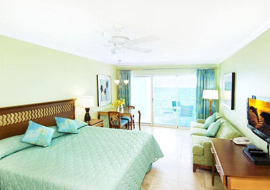 A hotel room with a king size bed , couch , table and television.