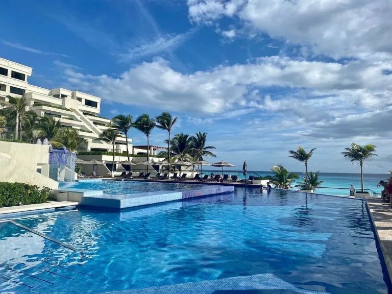 There is a large swimming pool in the middle of a resort.