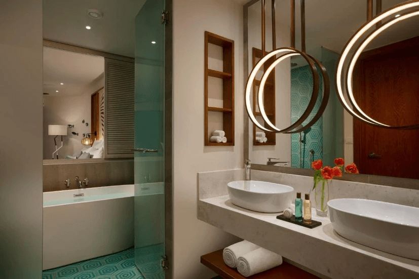 A bathroom with two sinks , a tub and a mirror.