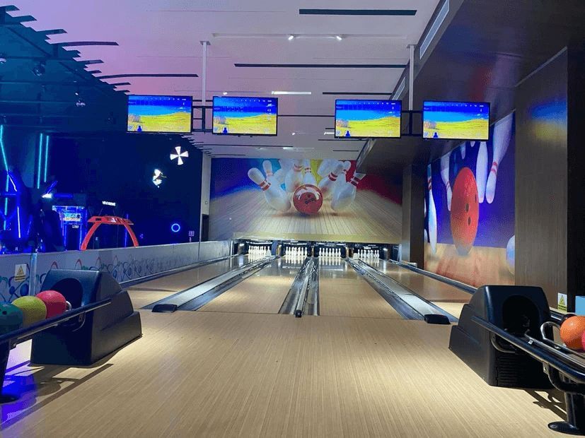 A bowling alley with a bowling ball going into the bowling alley