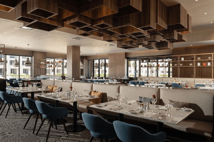 A restaurant with tables and chairs and a wooden ceiling.