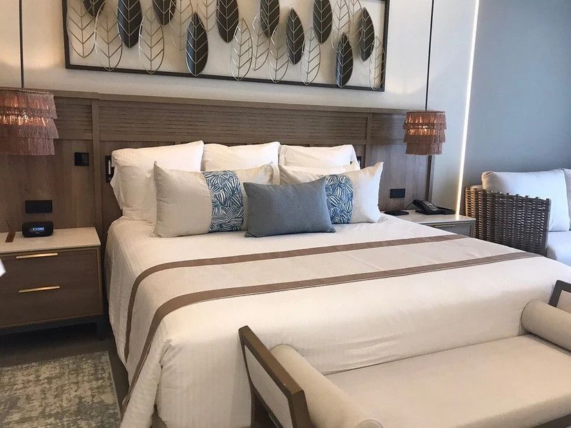 A hotel room with a king size bed and a bench.