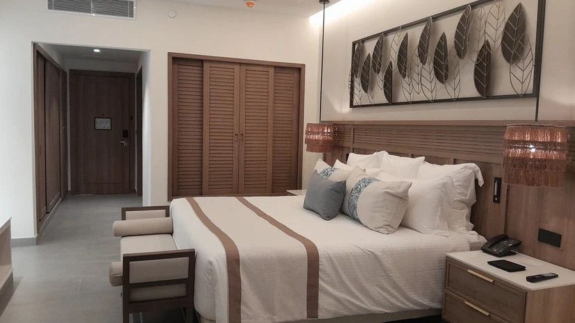 A hotel room with a king size bed and a bench.