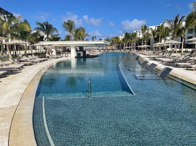 A large swimming pool surrounded by chairs and palm trees