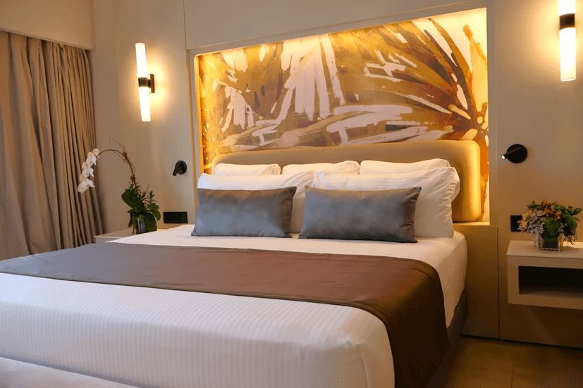 A hotel room with a large bed and a painting on the wall behind it.