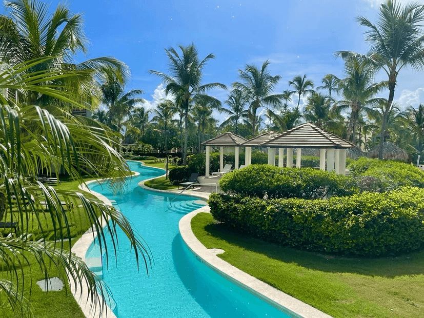 A large swimming pool surrounded by palm trees and a gazebo.