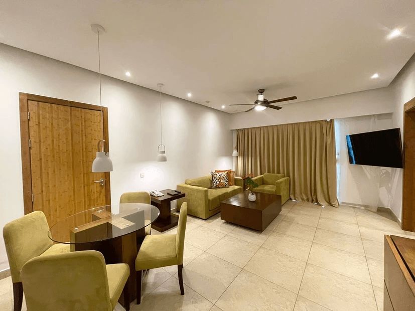 A living room with a couch , chairs , a table and a television.