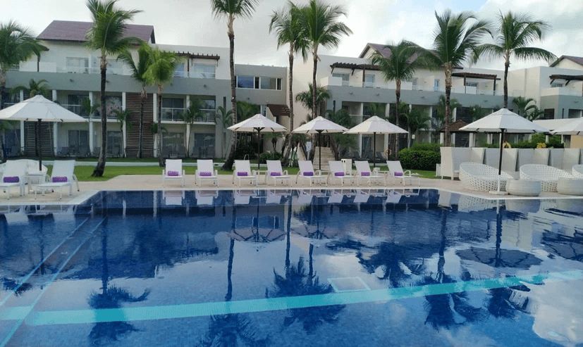 A large swimming pool surrounded by chairs and umbrellas