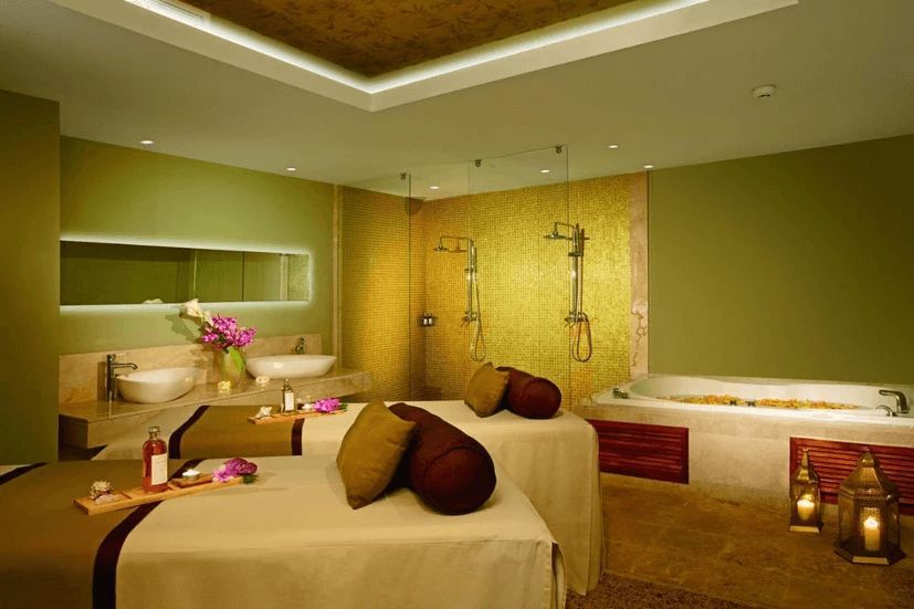 A spa room with two beds , a tub and a shower.