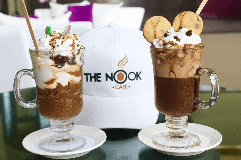 Two cups of food are on a table with the nook cafe logo in the background