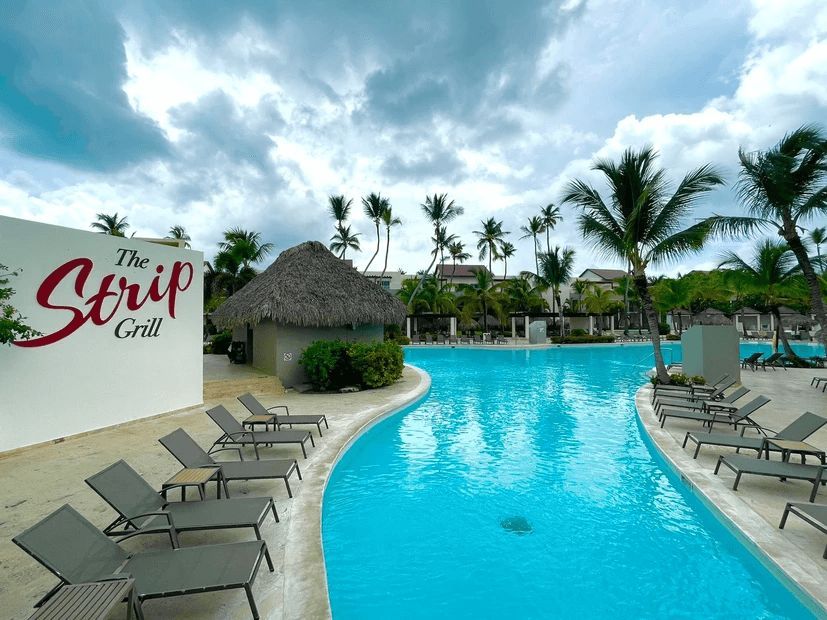 A large swimming pool with a sign that says the strip grill