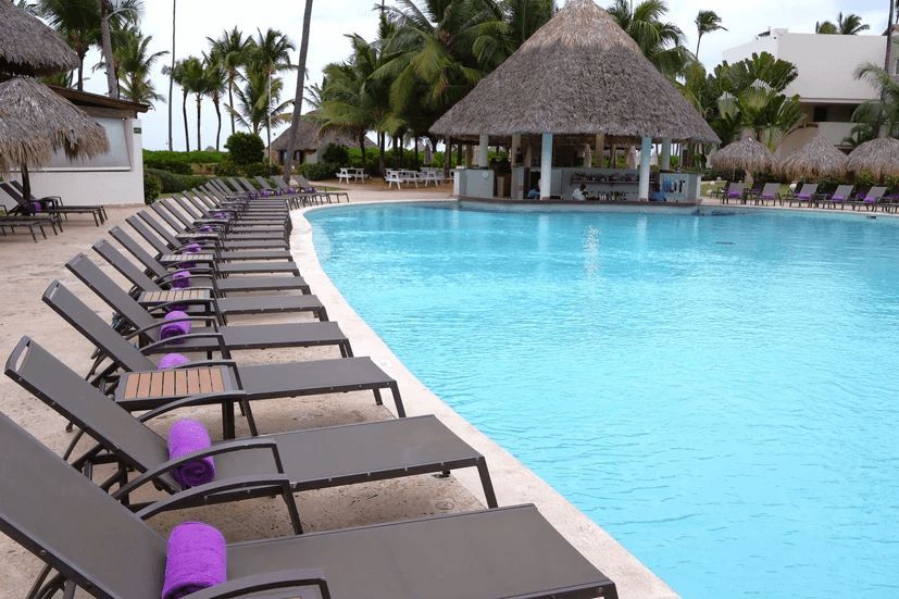 A large swimming pool surrounded by chairs and umbrellas