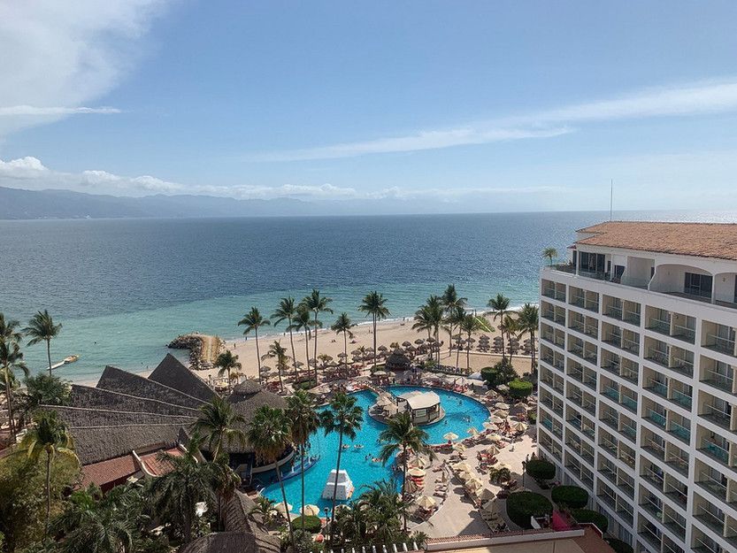 An aerial view of a hotel with a large pool in the middle of the beach.