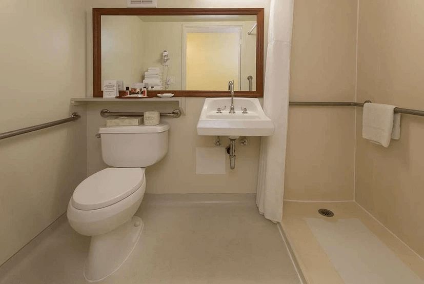 A bathroom with a toilet , sink and shower.