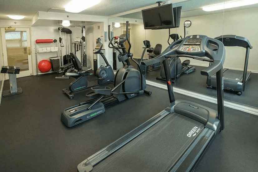 A gym with a treadmill , elliptical , and other exercise equipment.