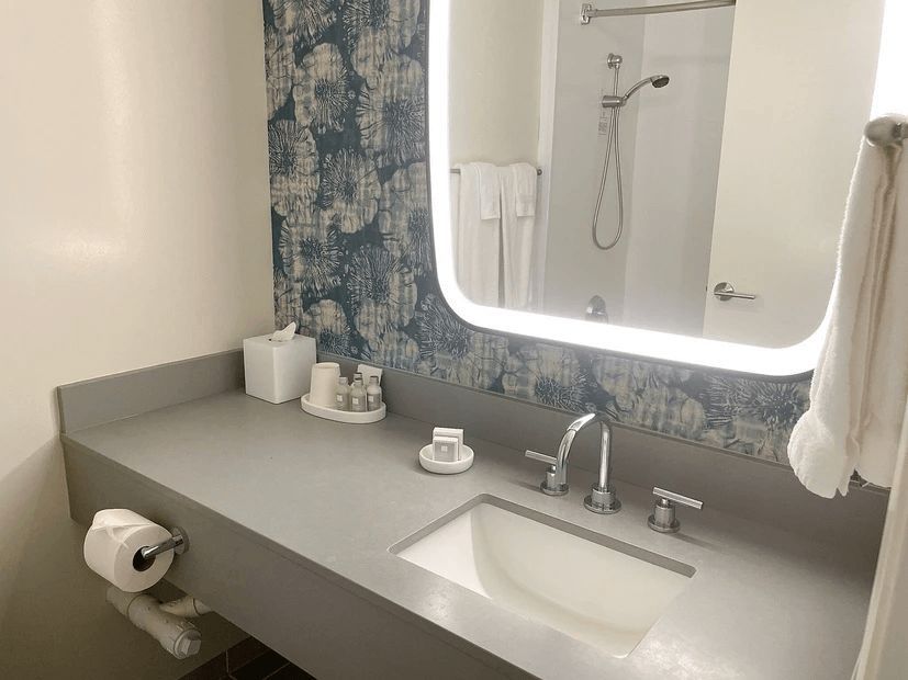 A bathroom with a sink , mirror and shower.
