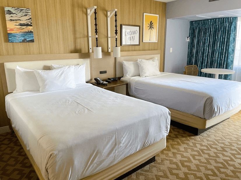 A hotel room with two beds and a table.