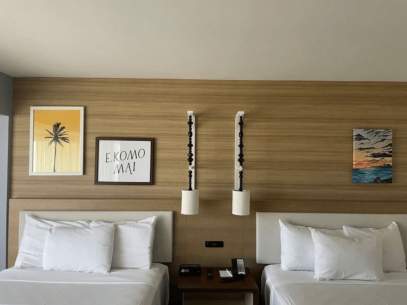 A hotel room with two beds and two paintings on the wall.