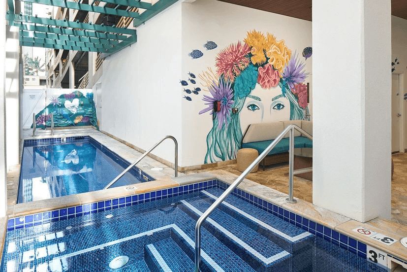 A swimming pool with stairs leading to it and a mural on the wall.