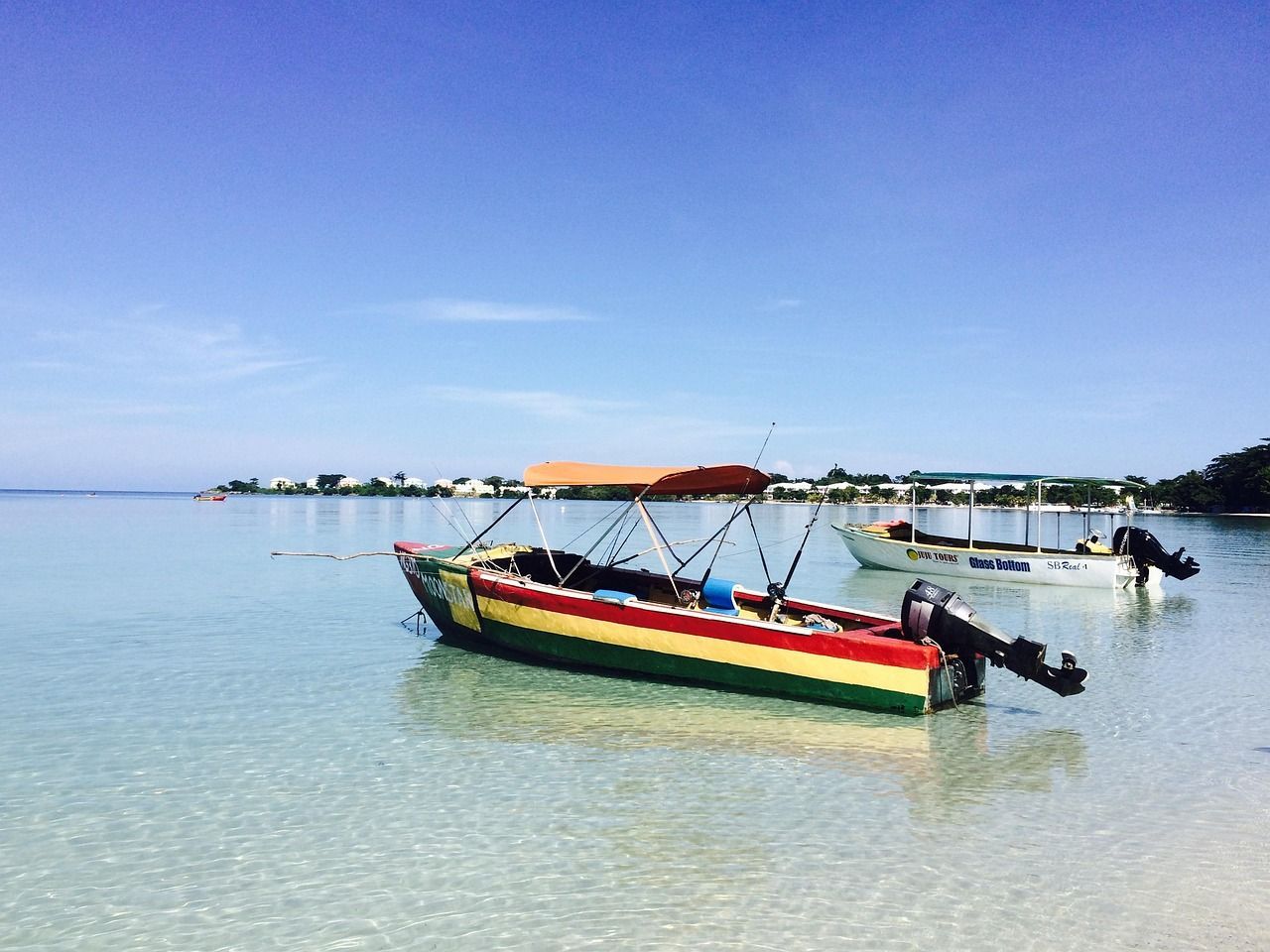 A colorful boat is floating on the water near a beach.