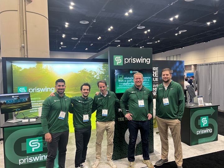 A group of men are posing for a picture in front of a priswing booth.