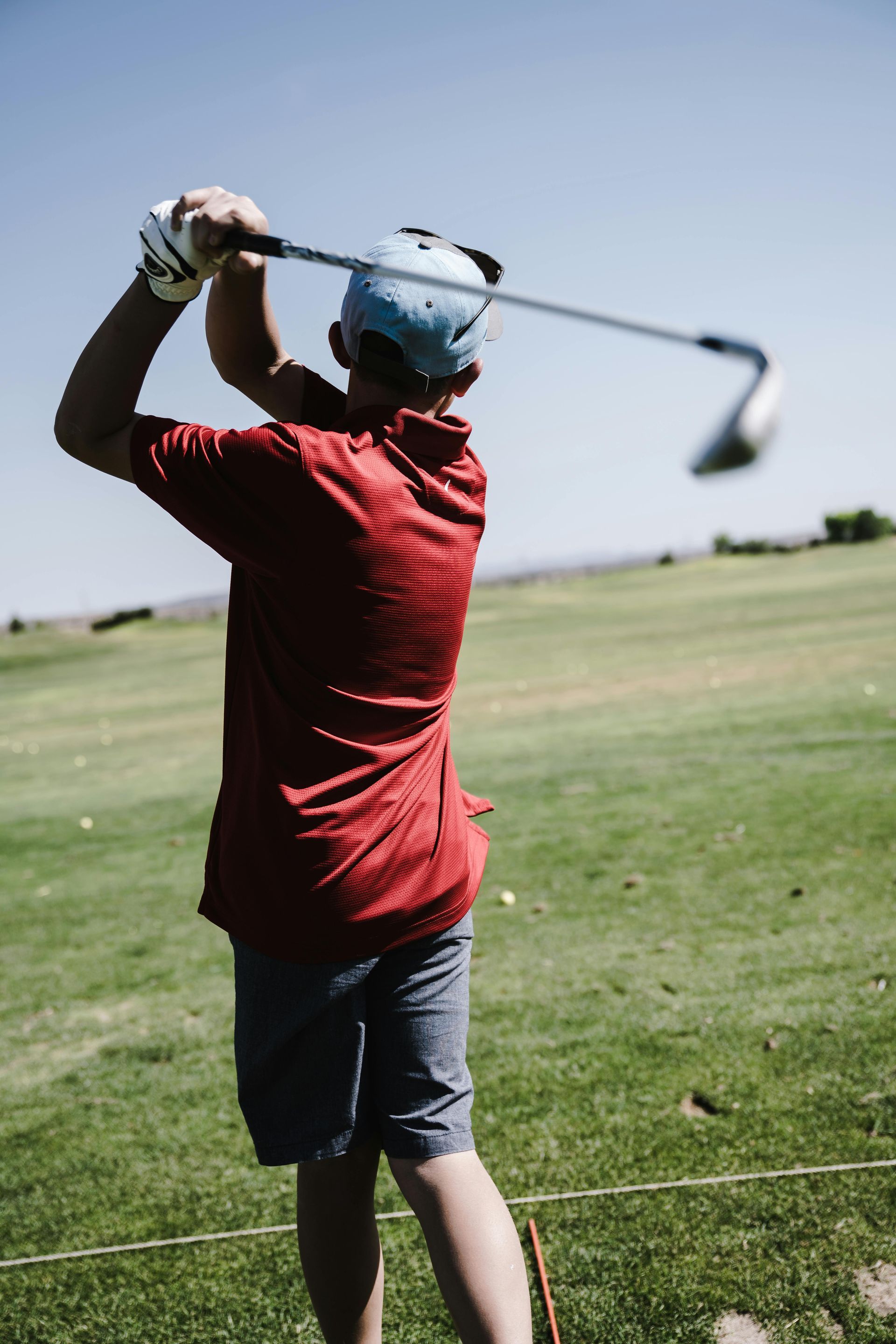 A man is swinging a golf club on a golf course.
