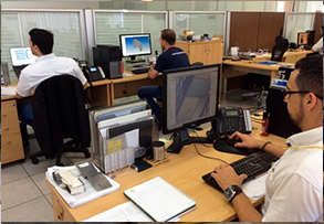 A group of men are sitting at desks in an office working on computers