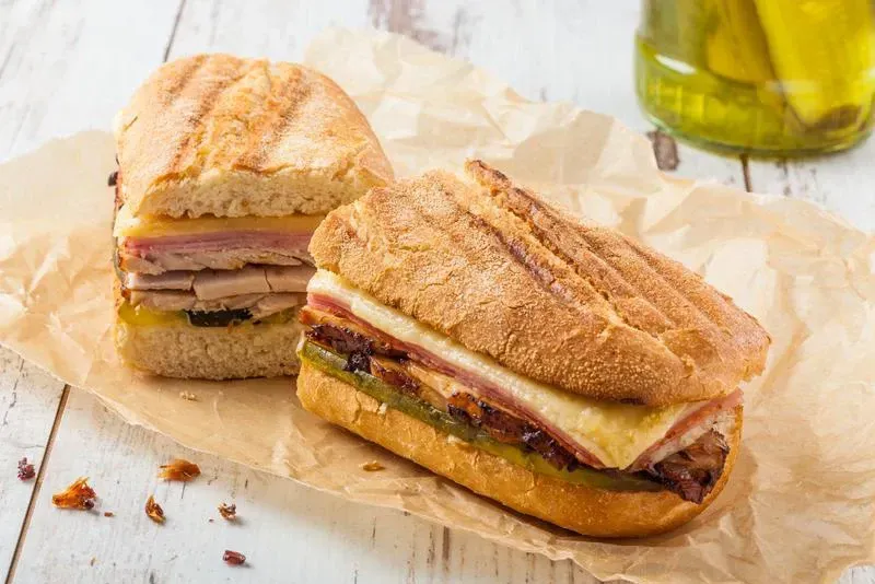 Two sandwiches are sitting on a piece of paper on a table.