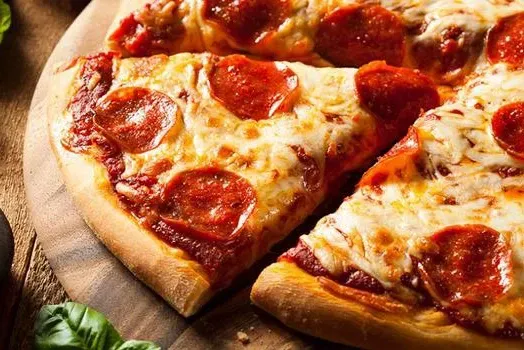 A pepperoni pizza with a slice taken out of it is on a wooden cutting board.
