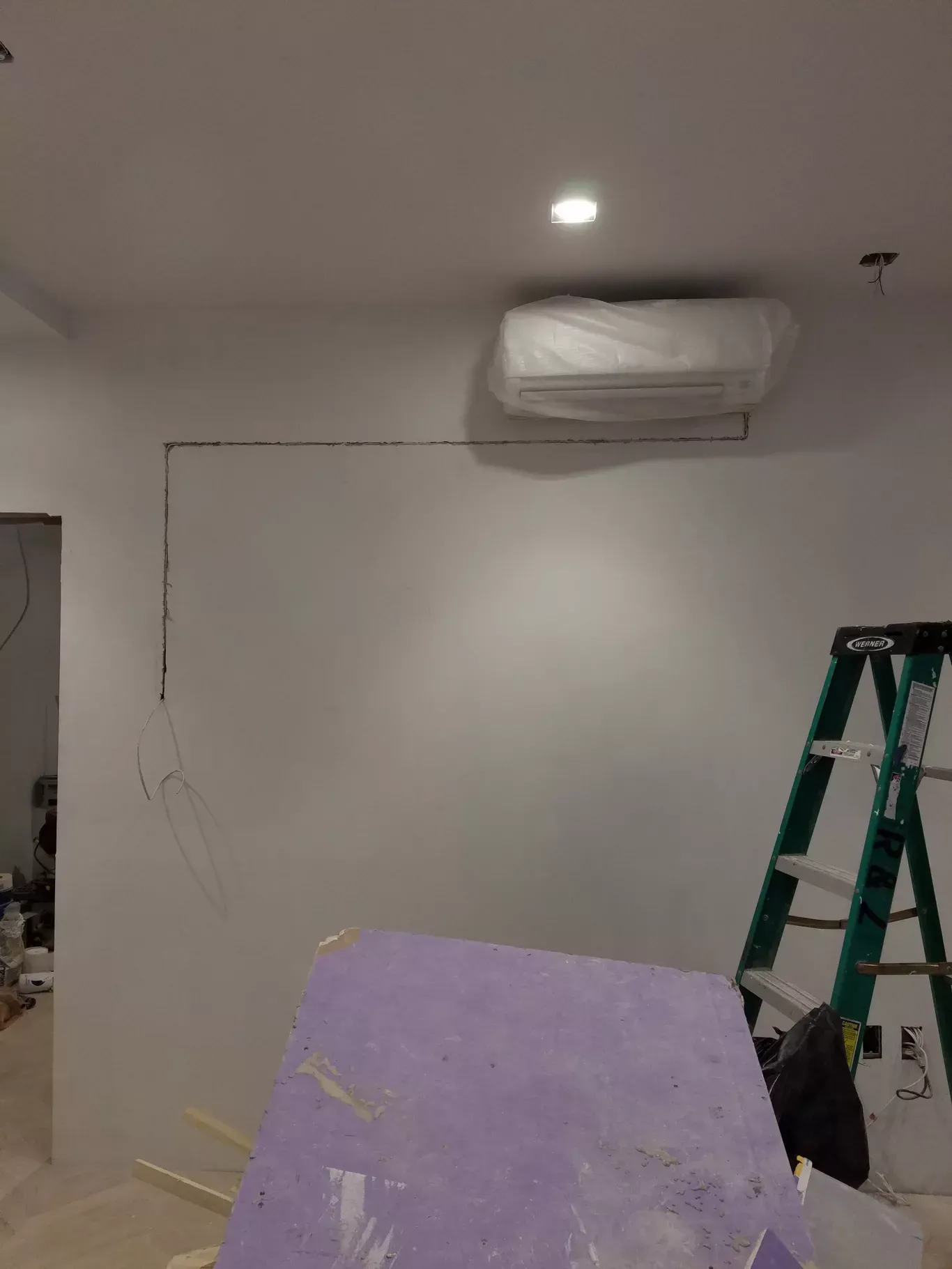 A room with a ladder and a white wall.