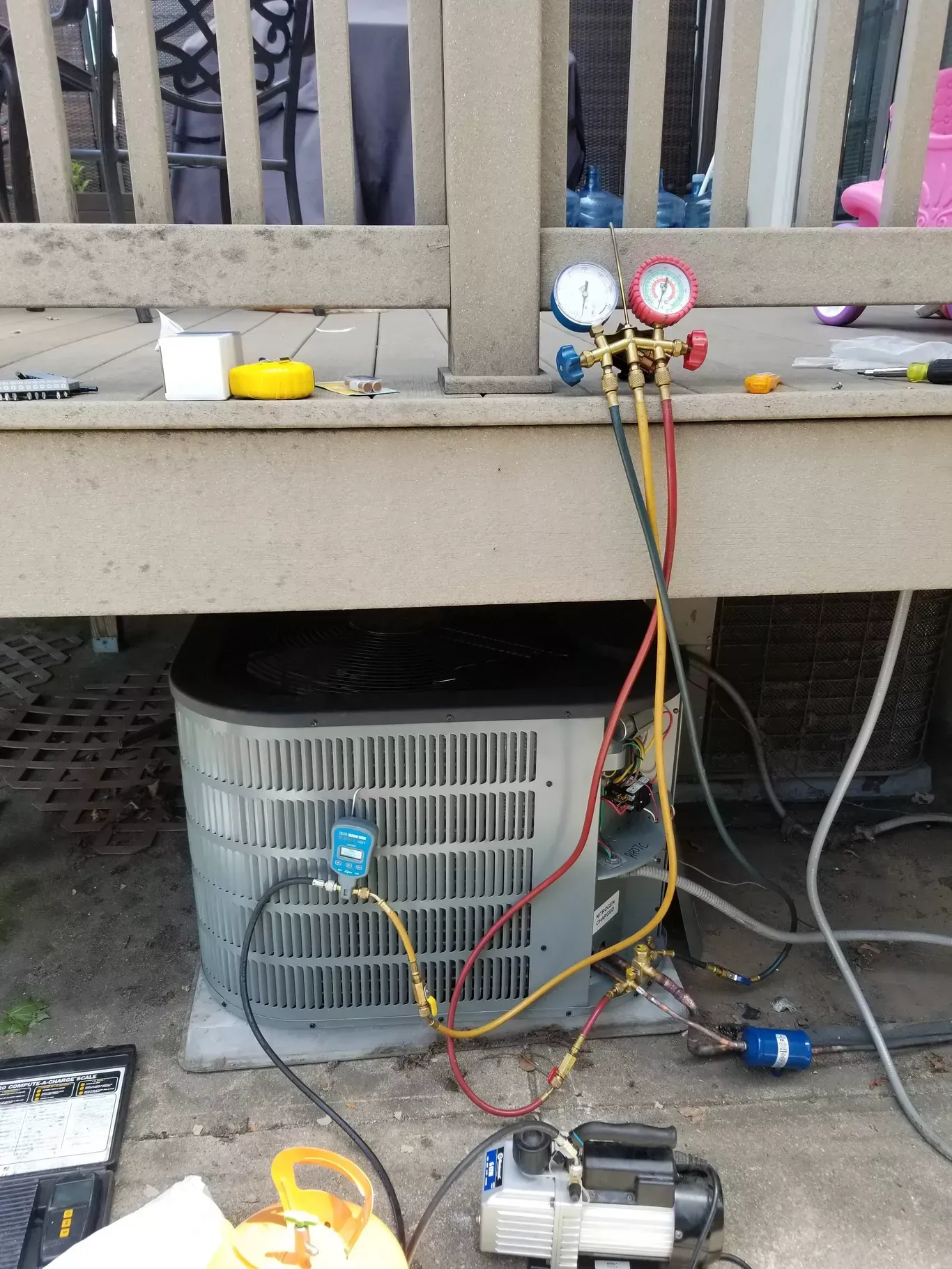 An air conditioner is being installed on a deck with a vacuum pump attached to it.