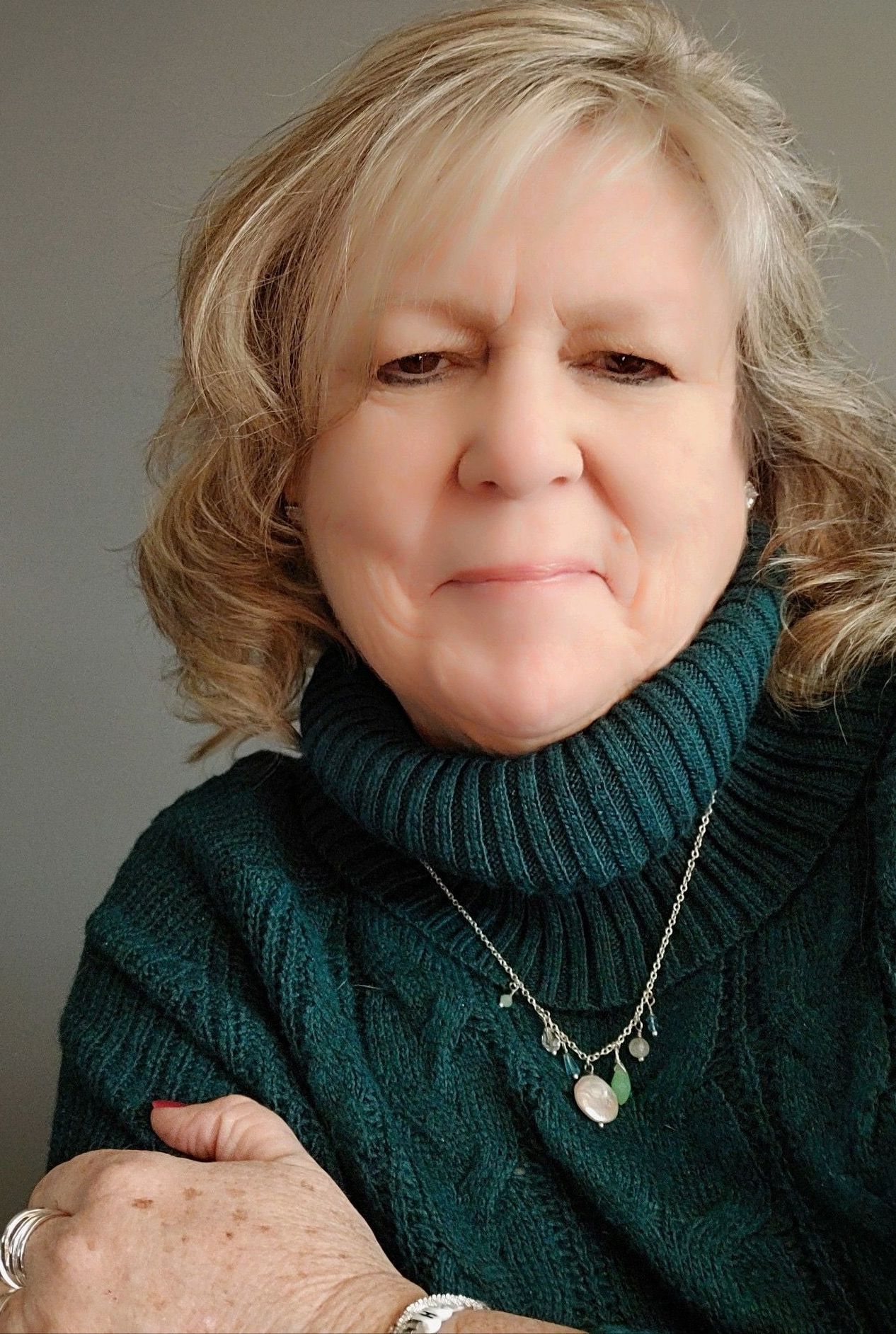 a woman is wearing a green sweater and a necklace .
