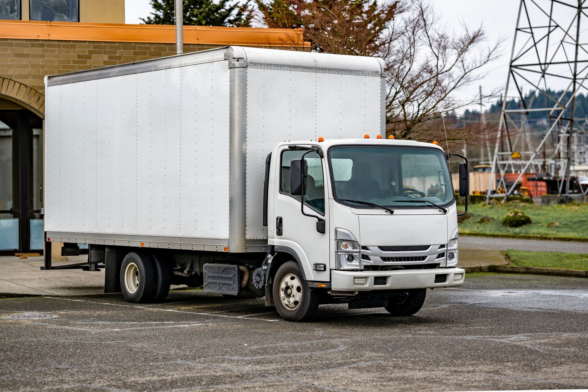 Man driving a truck, wearing an orange safety vest, looking focused, industrial setting.